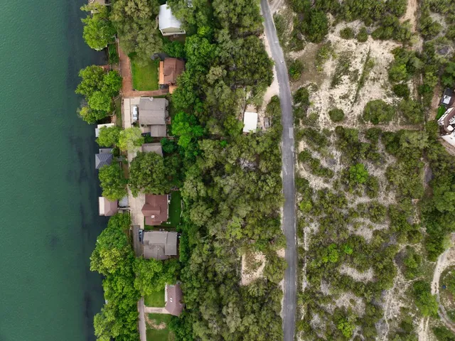 an aerial view of residential houses with outdoor space and trees all around