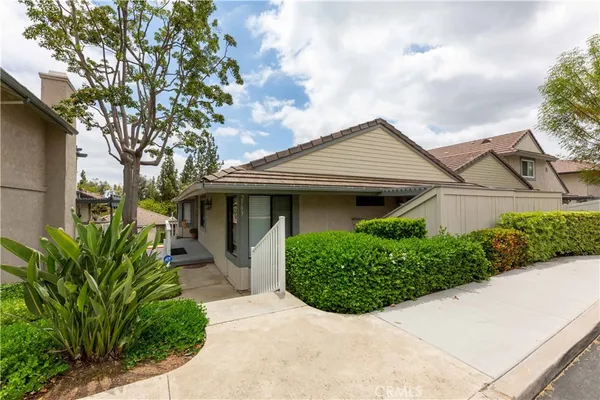 a view of a house with a small yard plants and a large tree