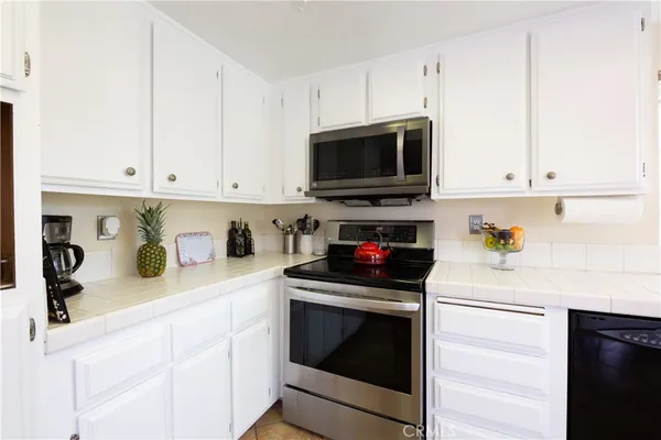 a kitchen with granite countertop white cabinets and stainless steel appliances