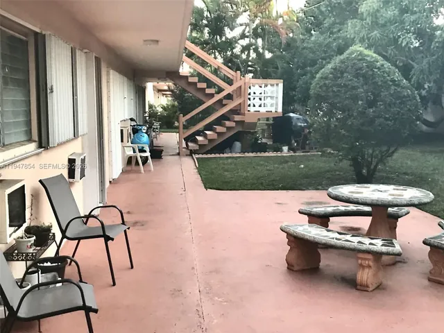 a view of a patio with table and chairs with wooden floor and fence