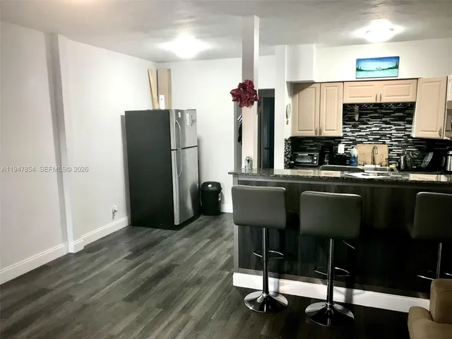 a kitchen with stainless steel appliances a dining table chairs refrigerator and sink