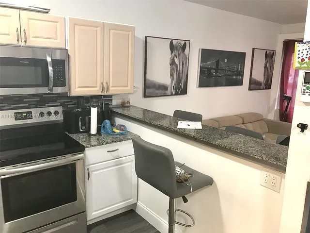 a kitchen with granite countertop a sink stove and microwave