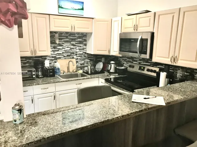 a kitchen with granite countertop a sink a stove and cabinets