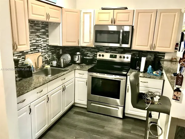 a kitchen with stainless steel appliances a stove a sink and white cabinets