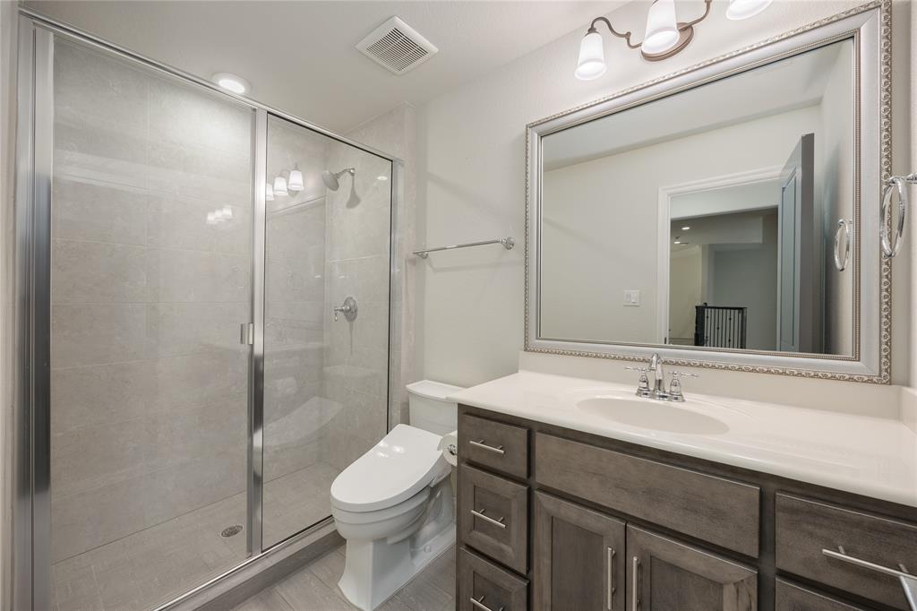 918 Sydney Lane Allen, TX 75013 - Photo 26 of 40 The bathroom 3 features a glass-enclosed shower with light-colored tile, a vanity with a white countertop and dark wood cabinetry, and a large framed mirror with an ornate border