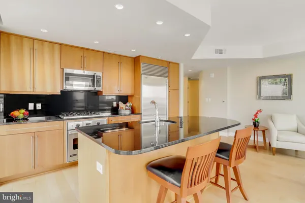 a kitchen with stainless steel appliances granite countertop a stove top oven a sink a dining table and chairs