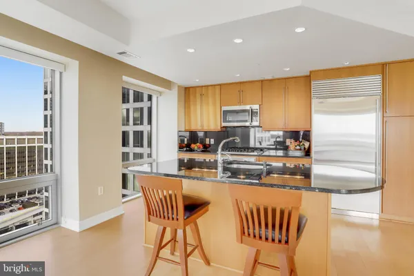 a kitchen with stainless steel appliances granite countertop a sink refrigerator and cabinets