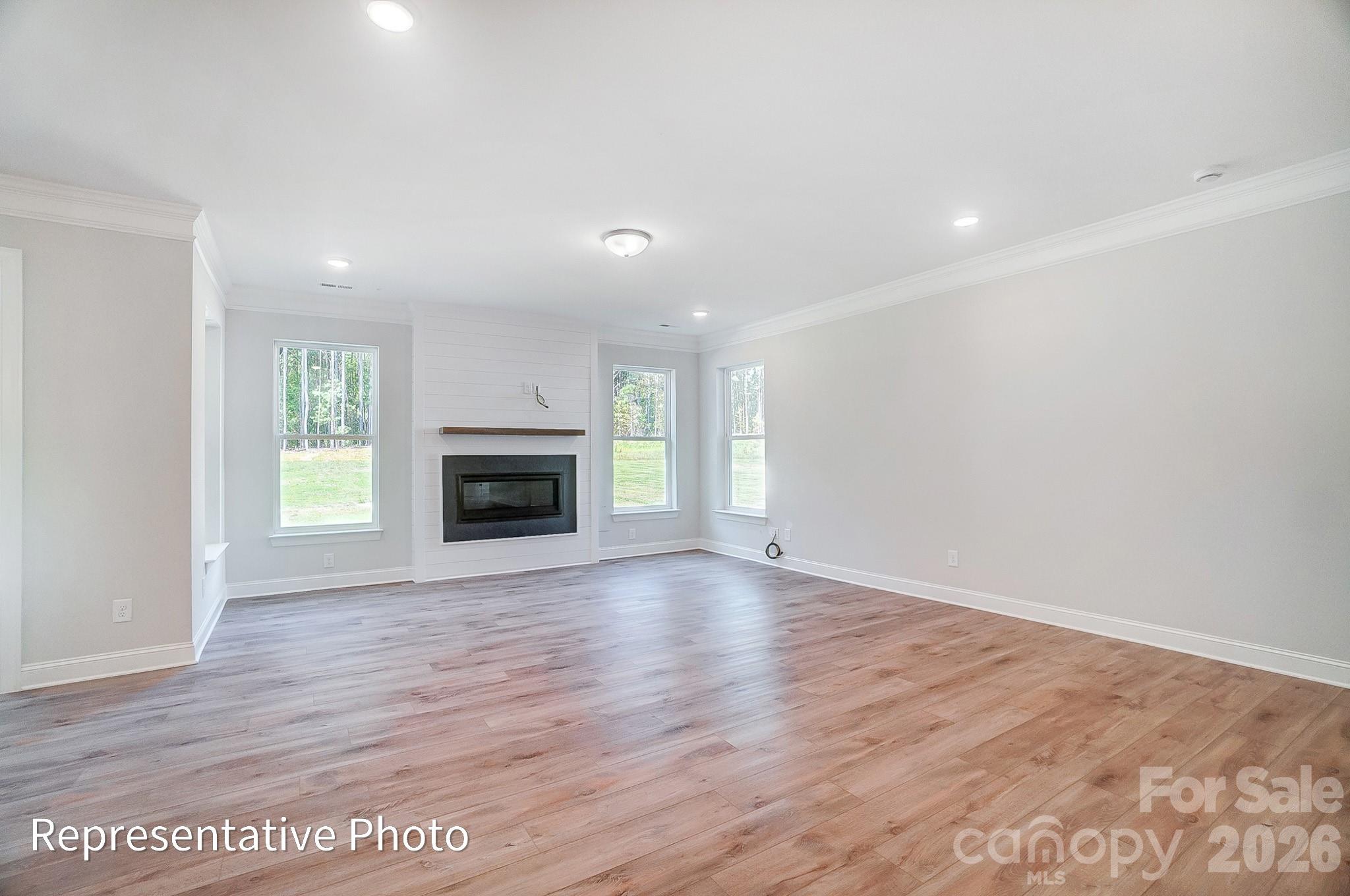 5058 Mclaughlin Loop Waxhaw, NC 28173 - Photo 16 of 42 an empty room with wooden floor fireplace and windows