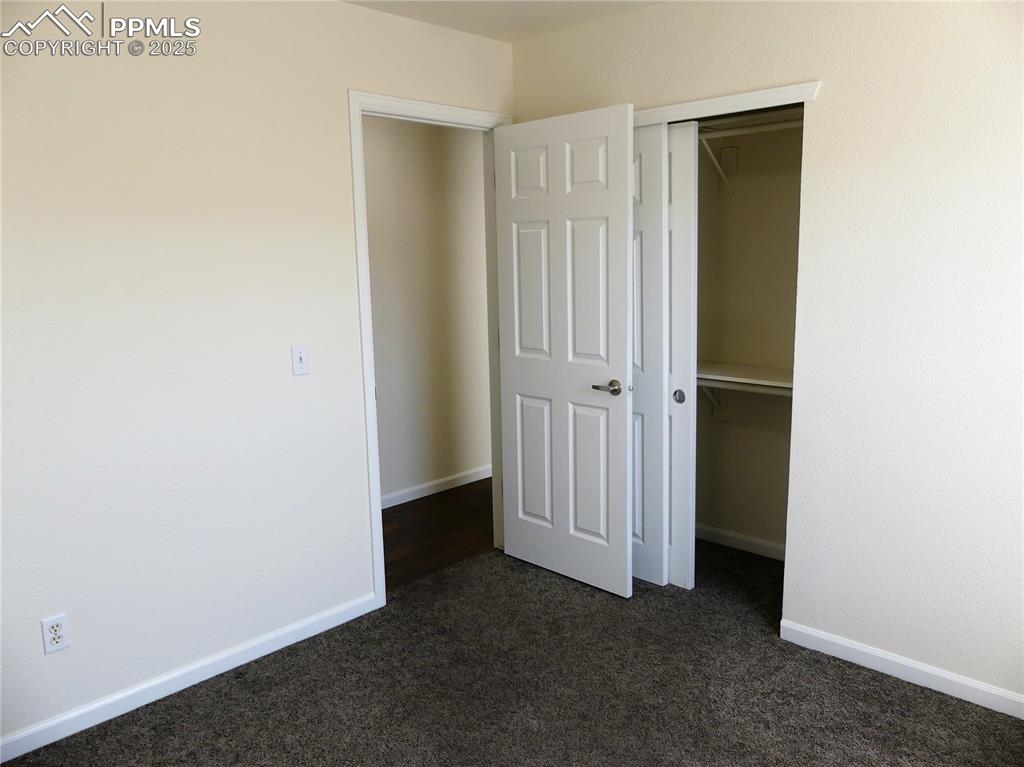 1054 Kara Ridge Point Colorado Springs, CO 80907 - Photo 22 of 33 Unfurnished bedroom with baseboards, a closet, and dark carpet