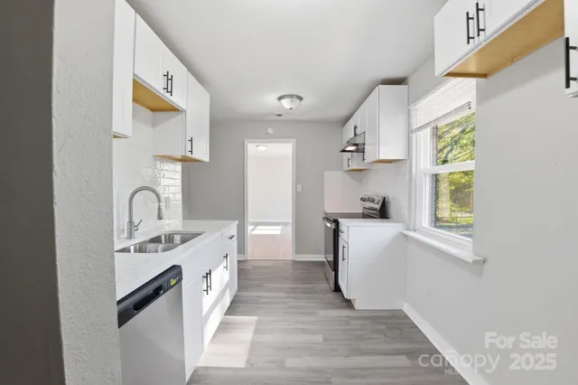 a large white kitchen with a sink a window and stainless steel appliances