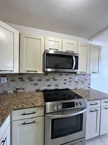 a kitchen with granite countertop a stove top oven microwave and cabinets