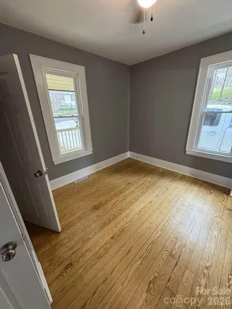 a view of an empty room with a window and wooden floor