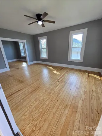 a view of empty room with wooden floor and fan