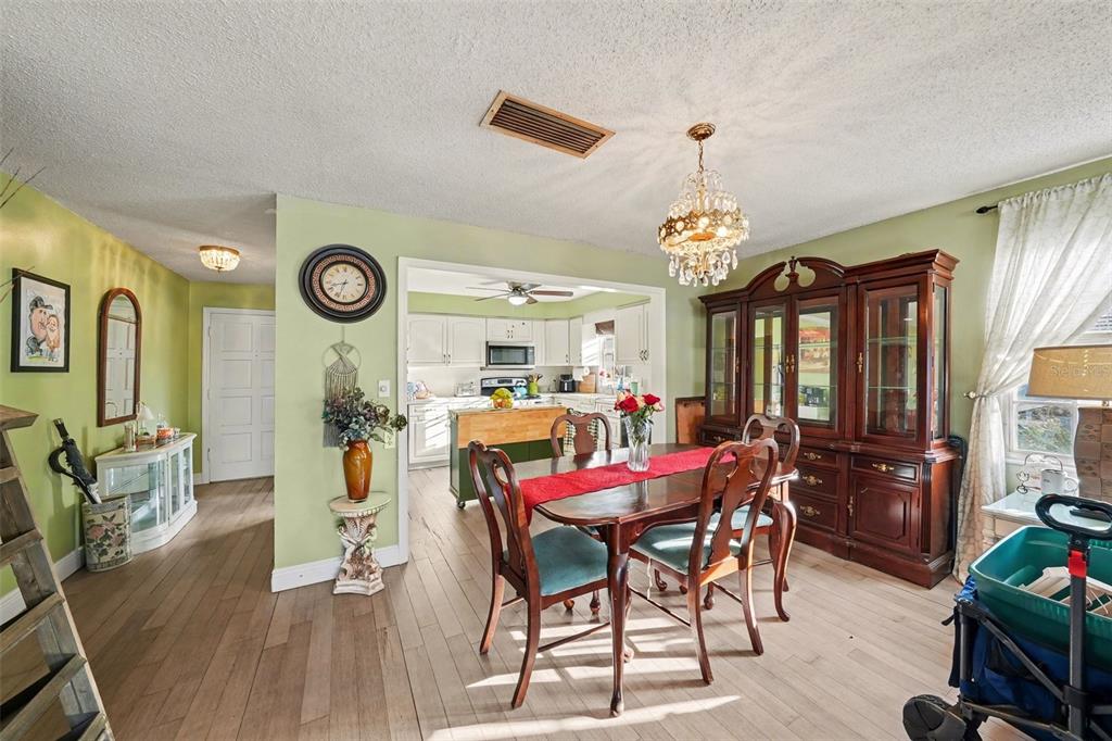 701 Poinsettia Road, Unit 240 Belleair, FL 33756 - Photo 9 of 30 a view of a dining room and livingroom with furniture wooden floor a rug a painting and a chandelier