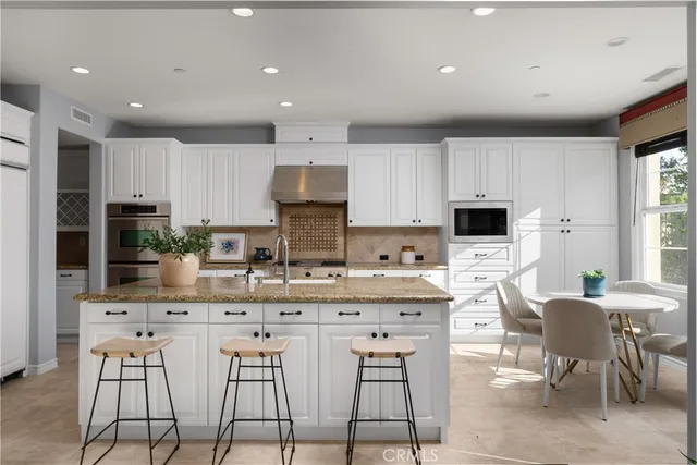 a kitchen with stainless steel appliances granite countertop a stove a sink a microwave a refrigerator and cabinets