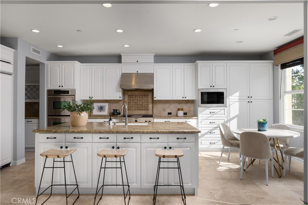 7 Waltham Road Ladera Ranch, CA 92694 - Photo 11 of 55 a kitchen with stainless steel appliances kitchen island granite countertop a stove a sink a refrigerator and white cabinets with wooden floor