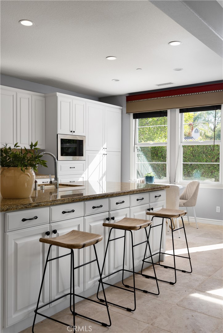 7 Waltham Road Ladera Ranch, CA 92694 - Photo 14 of 55 a kitchen with stainless steel appliances kitchen island granite countertop a stove a sink and a microwave