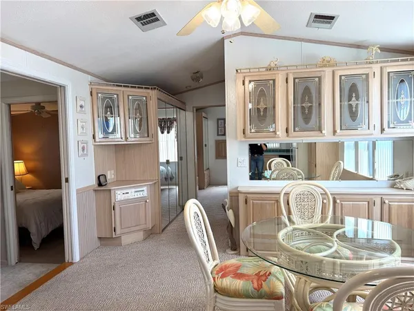 a living room with stainless steel appliances furniture a chandelier and a kitchen view