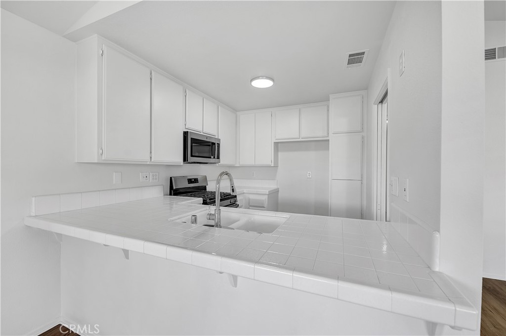 27042 Rangewood Street Menifee, CA 92586 - Photo 11 of 22 a kitchen with a sink stainless steel appliances and cabinets