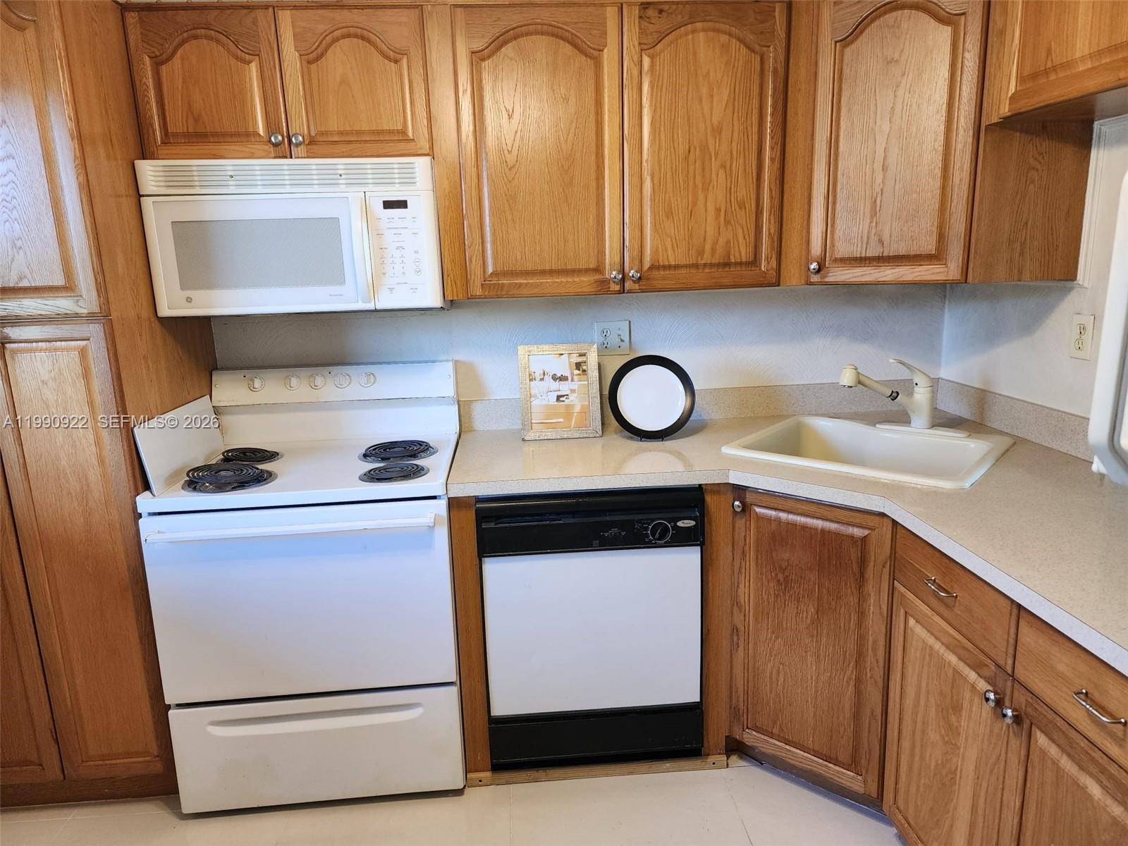 8370 Sands Point Boulevard, Unit H303 Tamarac, FL 33321 - Photo 2 of 7 a kitchen with granite countertop cabinets and white appliances