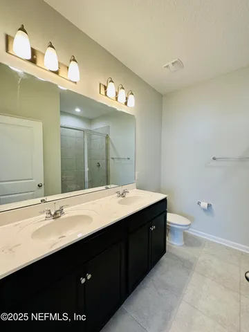 a bathroom with a double vanity sink toilet and a mirror