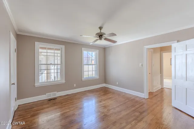 a view of an empty room with a window and wooden floor