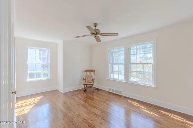 a view of an empty room with a window and wooden floor