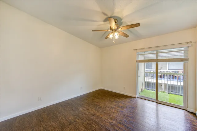 an empty room with wooden floor fan and windows