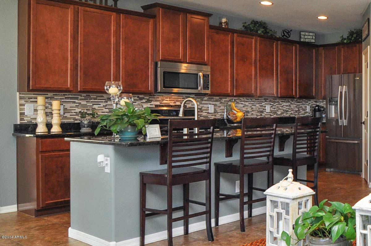 2304 North Alsap Road Buckeye, AZ 85396 - Photo 5 of 27 a kitchen with stainless steel appliances a table chairs refrigerator and cabinets