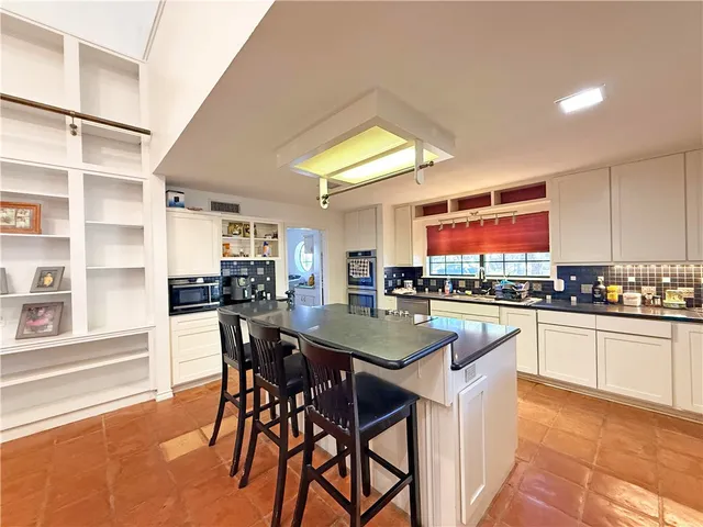 a kitchen with stainless steel appliances granite countertop table chairs sink and cabinets