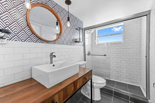 a bathroom with a sink a mirror a toilet and a shower