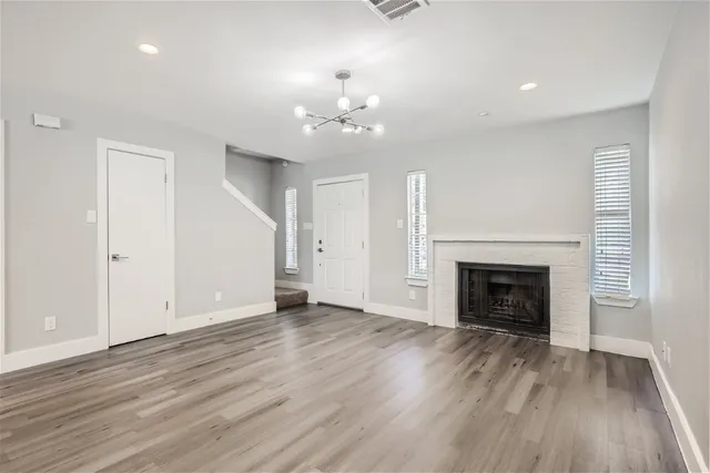 an empty room with wooden floor fireplace and window