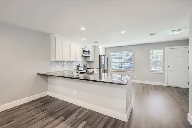 a kitchen with granite countertop wooden floors and white cabinets