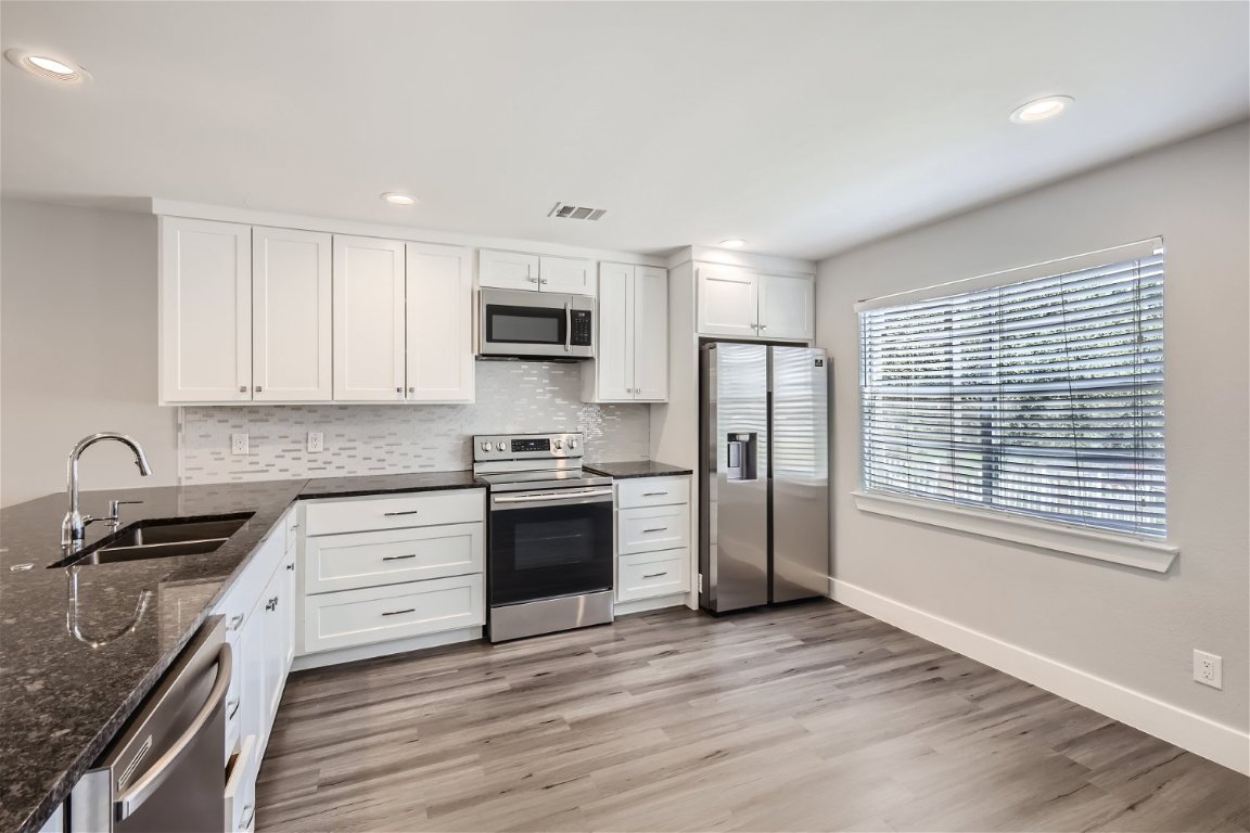 1830 River Crossing Circle, Unit D Austin, TX 78741 - Photo 8 of 27 a kitchen with kitchen island granite countertop a stove a sink and a refrigerator