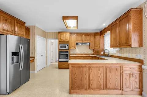 a kitchen with stainless steel appliances granite countertop a refrigerator a stove a sink and a microwave