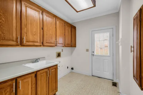 a utility room with a sink a cabinetry and a window