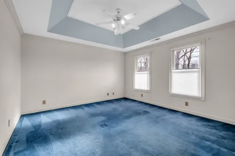 an empty room with wooden floor chandelier fan and windows