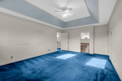 an empty room with chandelier fan and windows