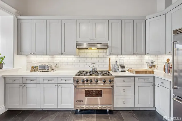 a kitchen with granite countertop white cabinets and stainless steel appliances