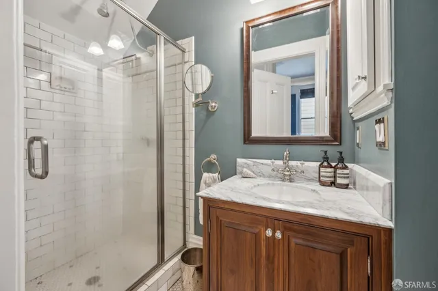 a bathroom with a sink a mirror a vanity and shower