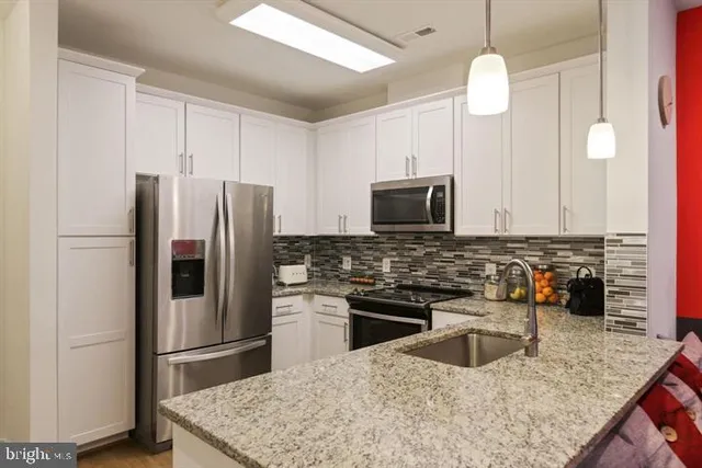 a kitchen with stainless steel appliances granite countertop a refrigerator a stove a sink and a microwave