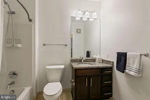 a bathroom with a granite countertop sink toilet a mirror and shower