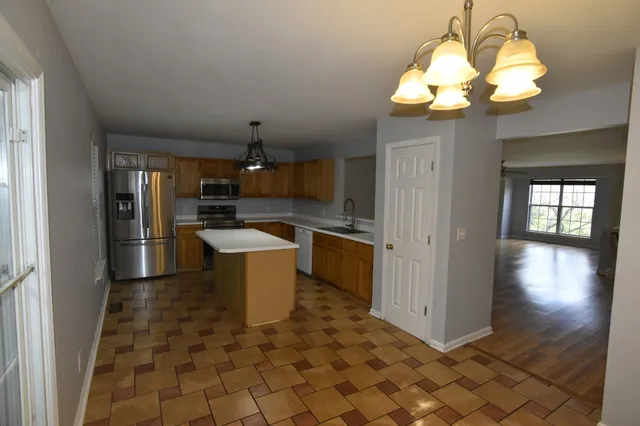 a kitchen with granite countertop a stove a refrigerator and a dining table with wooden floor
