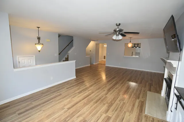 a view of a livingroom with a fireplace wooden floor and a ceiling fan