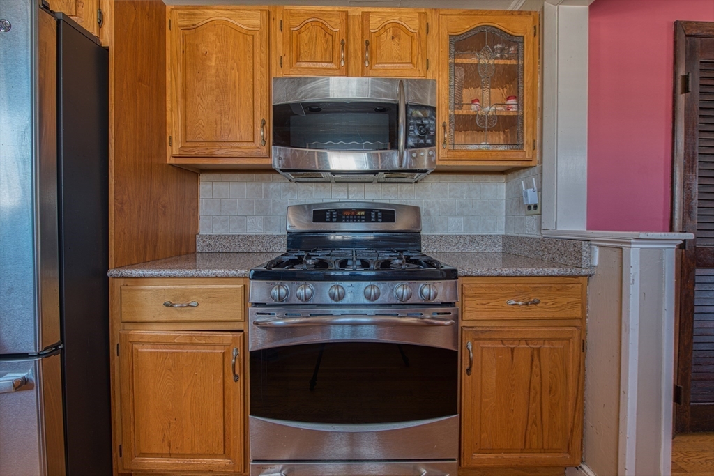 12 Brewster Road Randolph, MA 02368 - Photo 9 of 27 a kitchen with stainless steel appliances granite countertop a stove microwave and cabinets