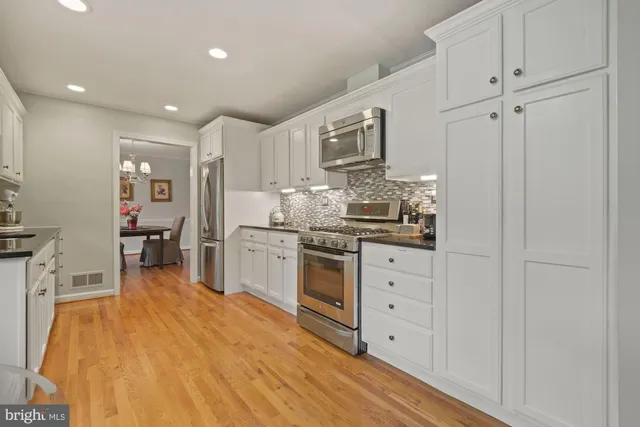 a kitchen with stainless steel appliances white cabinets and wooden floors