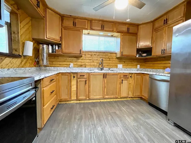 a kitchen with stainless steel appliances granite countertop wooden cabinets and a sink