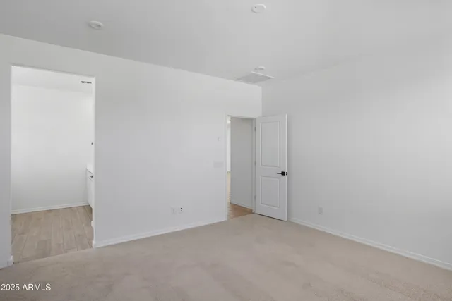 a view of an empty room with closet and a window