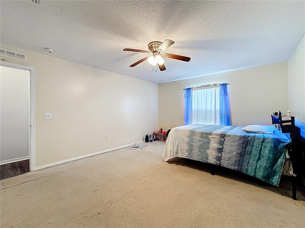 2620 Hunley Loop Kissimmee, FL 34743 - Photo 31 of 52 a bed sitting in a bedroom next to a window and a chandelier