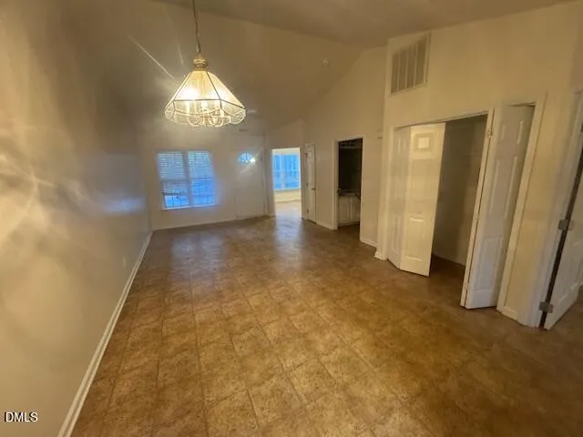 an empty room with chandelier fan and windows